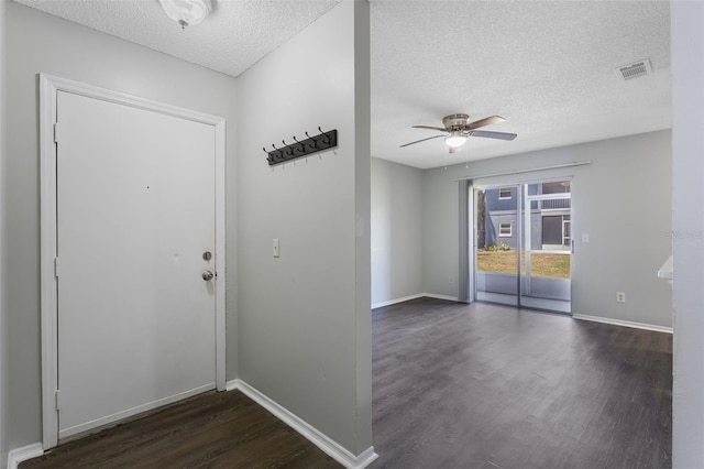 entryway with dark wood-style flooring, a textured ceiling, a ceiling fan, baseboards, and visible vents