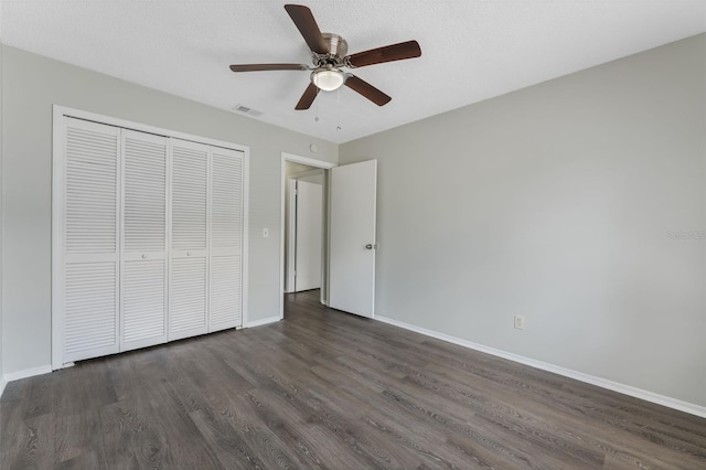 unfurnished bedroom with a closet, baseboards, visible vents, and dark wood-type flooring