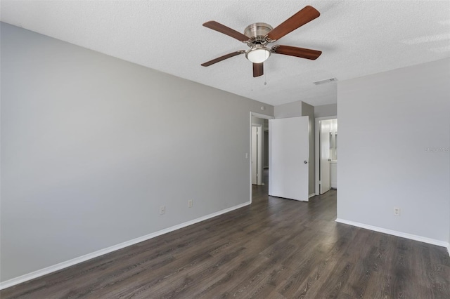empty room featuring baseboards, a ceiling fan, dark wood-style floors, and visible vents