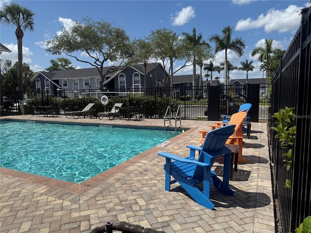 community pool featuring fence, a patio area, and a residential view