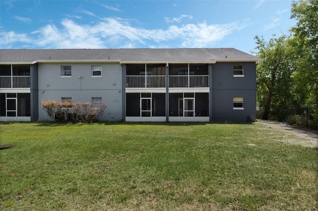 back of house with a sunroom, a lawn, and stucco siding