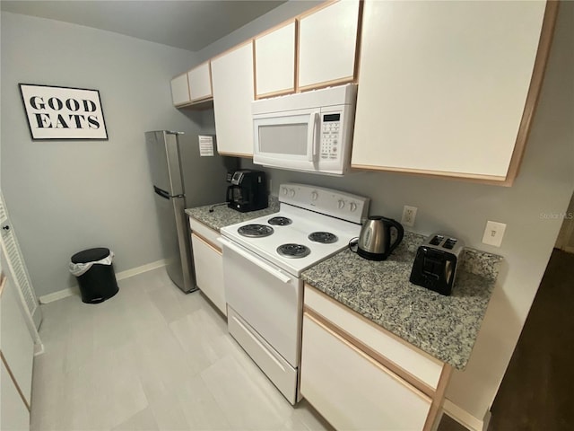 3147 Britannia Blvd Unit A, Kissimmee, FL 34747 - kitchen with baseboards, light stone countertops, white appliances, and white cabinetry