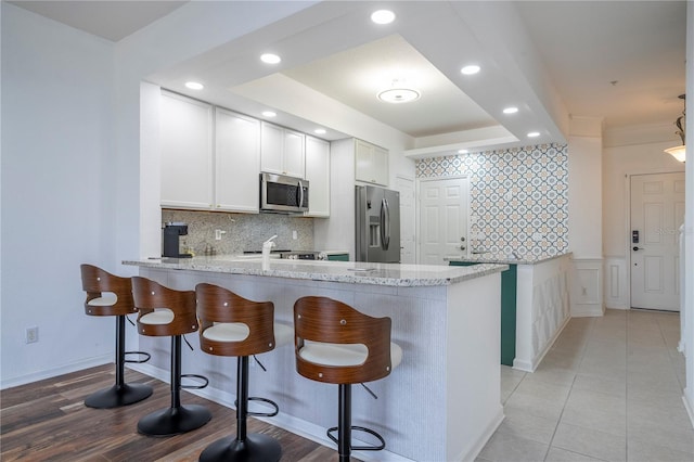 3567 Shallot Dr Unit 103, Orlando, FL 32835 - kitchen with appliances with stainless steel finishes, a peninsula, decorative backsplash, a breakfast bar, and recessed lighting