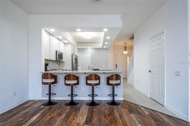 3567 Shallot Dr Unit 103, Orlando, FL 32835 - kitchen featuring appliances with stainless steel finishes, a breakfast bar area, a peninsula, decorative backsplash, and recessed lighting