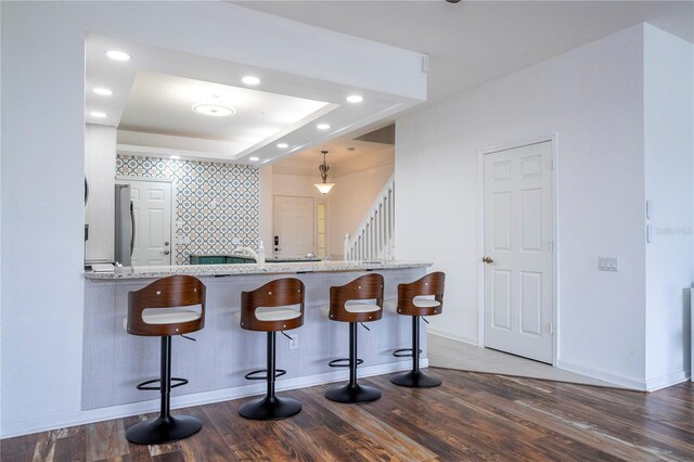 3567 Shallot Dr Unit 103, Orlando, FL 32835 - kitchen with freestanding refrigerator, wood finished floors, a breakfast bar area, baseboards, and recessed lighting