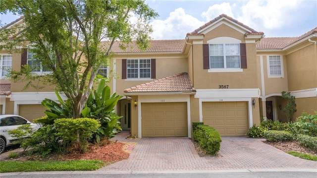 3567 Shallot Dr Unit 103, Orlando, FL 32835 - townhome / multi-family property featuring a tile roof, stucco siding, driveway, and a garage