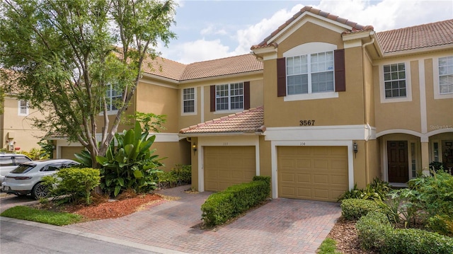 3567 Shallot Dr Unit 103, Orlando, FL 32835 - view of property with a tile roof, stucco siding, driveway, and an attached garage