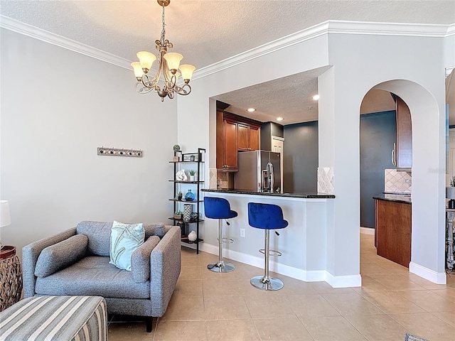 7509 Mourning Dove Cir Unit 203, Reunion, FL 34747 - interior space featuring light tile patterned flooring, dark countertops, stainless steel fridge, a kitchen breakfast bar, and decorative backsplash