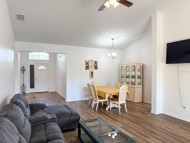 living area with visible vents, wood finished floors, baseboards, ceiling fan with notable chandelier, and lofted ceiling