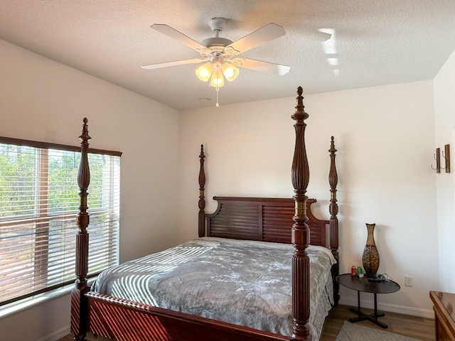bedroom with baseboards, a ceiling fan, a textured ceiling, and wood finished floors