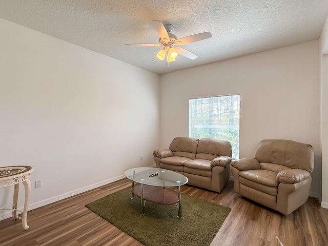 living area featuring baseboards, a textured ceiling, ceiling fan, and wood finished floors