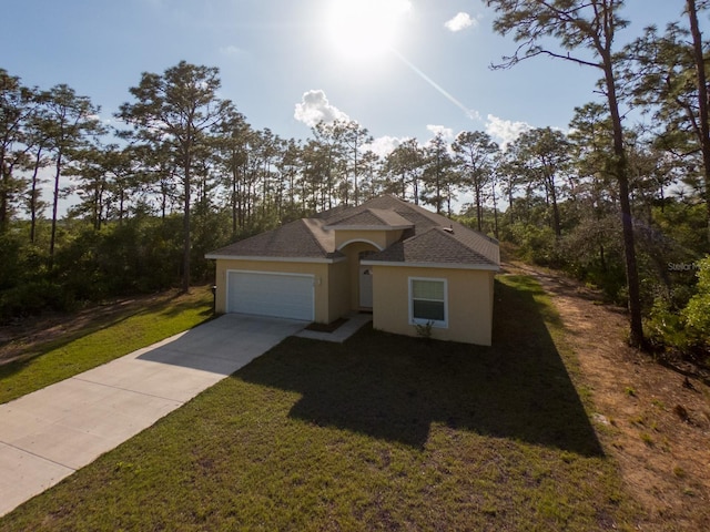 view of front of home with concrete driveway, a garage, a front yard, and stucco siding
