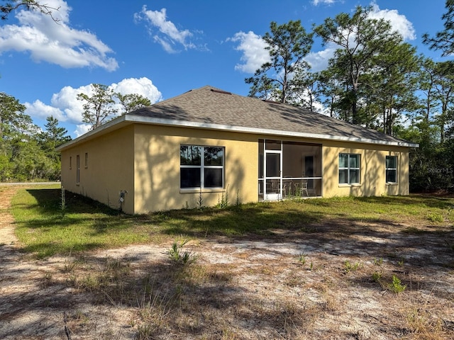 rear view of house featuring a shingled roof, a sunroom, and stucco siding