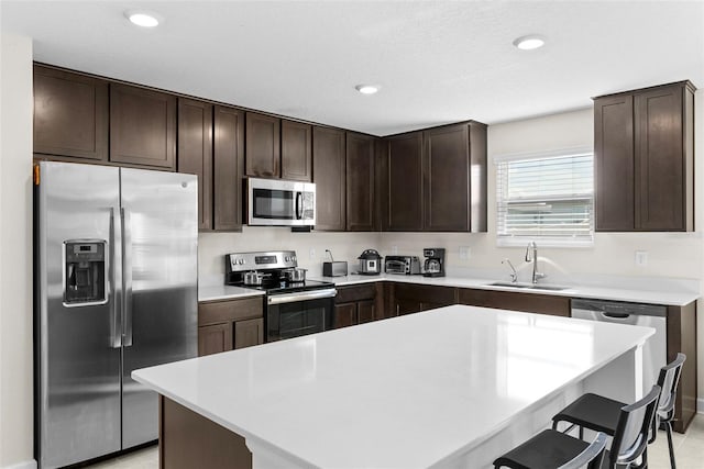 740 Simone Ct, Haines City, FL 33844 - kitchen with dark brown cabinetry, a breakfast bar, light countertops, a sink, and stainless steel appliances