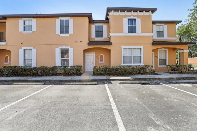 townhome / multi-family property with stucco siding and uncovered parking