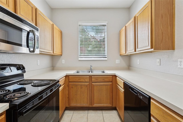 kitchen with a sink, light tile patterned floors, black appliances, and light countertops