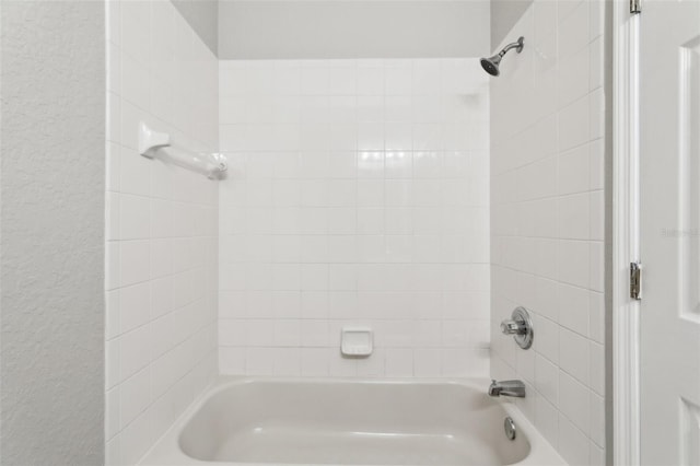 bathroom featuring shower / bath combination and a textured wall