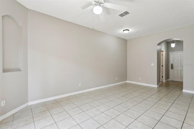 empty room with arched walkways, a ceiling fan, baseboards, light tile patterned floors, and visible vents