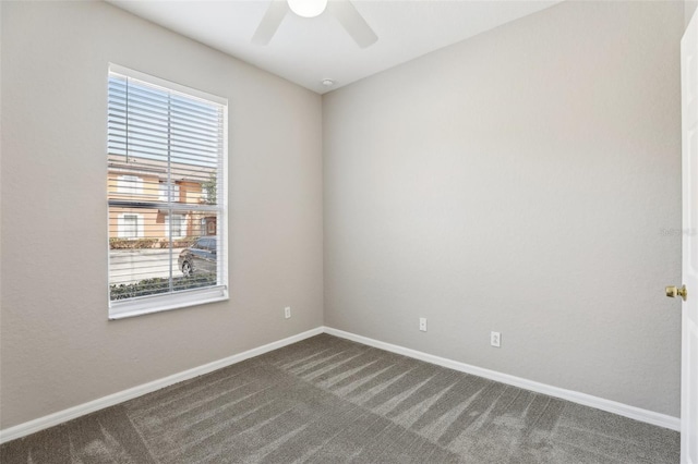 spare room with baseboards, a ceiling fan, and dark colored carpet