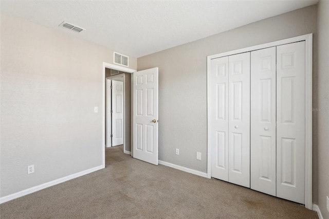 unfurnished bedroom featuring baseboards, carpet, a closet, and visible vents