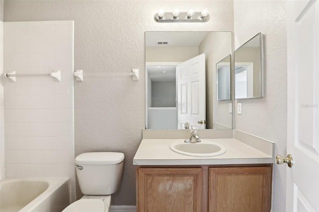 bathroom with vanity, a textured wall, toilet, and visible vents