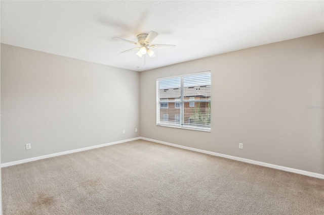 carpeted empty room featuring a ceiling fan and baseboards