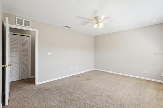 carpeted empty room featuring visible vents, baseboards, and ceiling fan