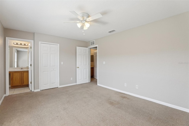 unfurnished bedroom featuring light colored carpet, baseboards, visible vents, and a sink