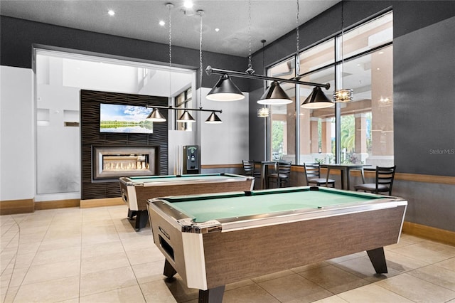 recreation room featuring a multi sided fireplace, pool table, tile patterned flooring, baseboards, and a high ceiling