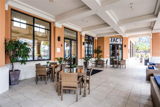 dining room with stone tile floors, beamed ceiling, french doors, and coffered ceiling