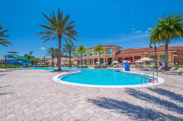 pool with a patio and a water slide
