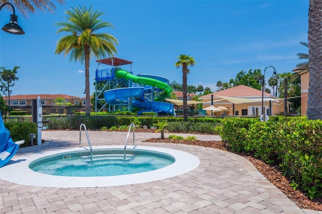 view of swimming pool with a water slide, a community hot tub, and playground community