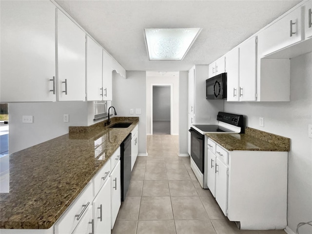 kitchen with white cabinets, a sink, dark stone countertops, light tile patterned floors, and black appliances
