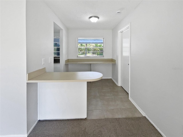 interior space with light countertops, a peninsula, baseboards, and light tile patterned floors