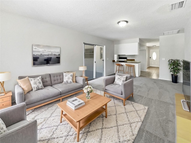 living room featuring visible vents, a textured ceiling, and light carpet