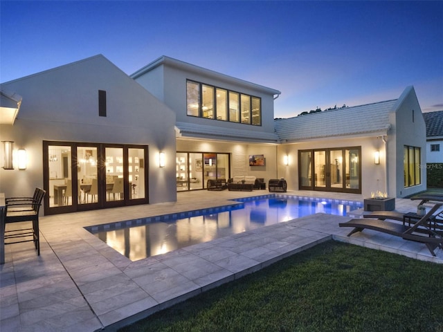 rear view of property with an outdoor hangout area, a patio, stucco siding, and an outdoor pool