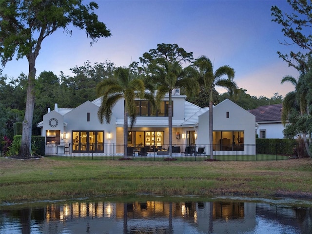 rear view of property with a water view, fence private yard, and stucco siding