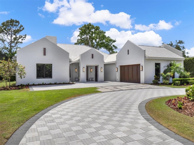 modern farmhouse with a garage, curved driveway, a tile roof, and a front lawn