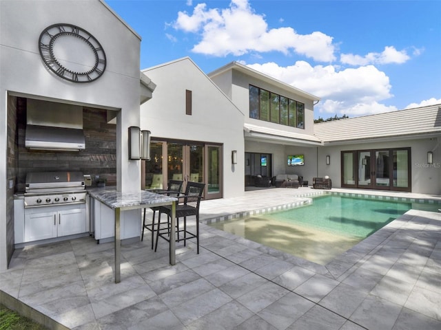 pool with grilling area, a patio, french doors, an outdoor kitchen, and outdoor wet bar