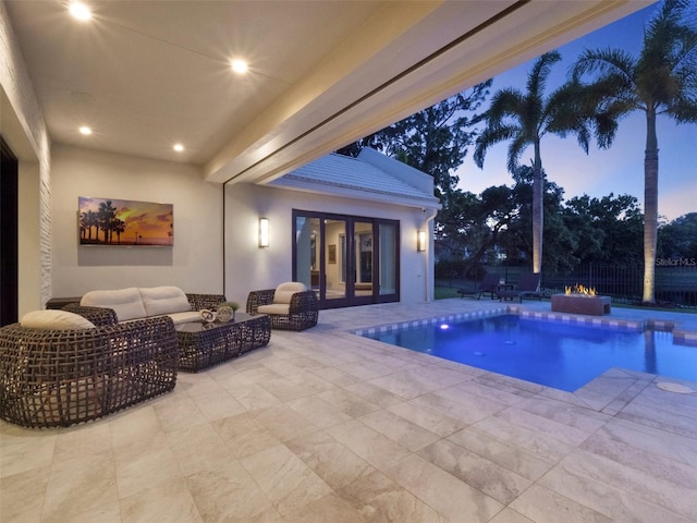 pool at dusk featuring an outdoor living space with a fire pit, fence, an outdoor pool, french doors, and a patio area