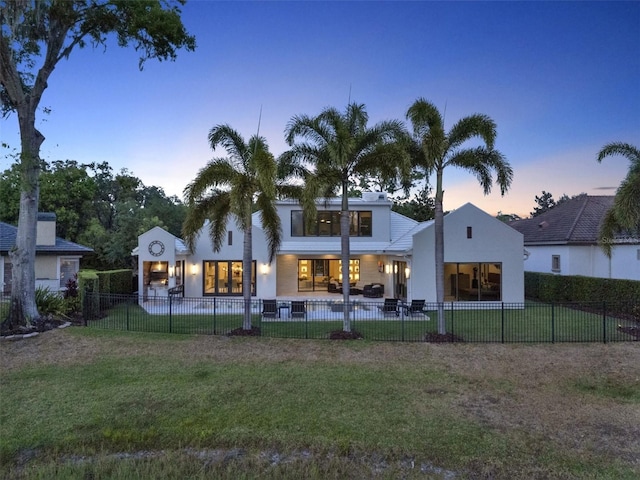 rear view of property featuring a fenced backyard, stucco siding, and a yard