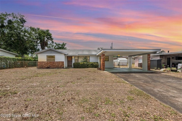 single story home with fence, a front yard, brick siding, concrete driveway, and a carport