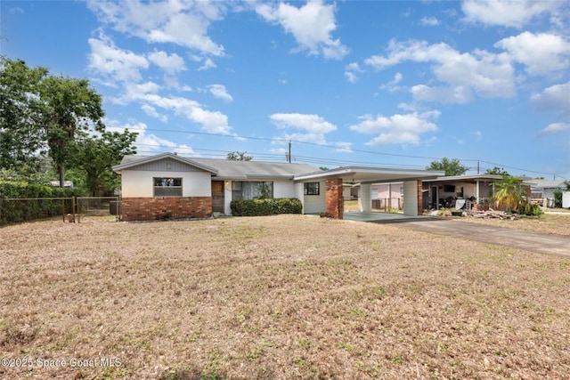 ranch-style house with fence, a front yard, brick siding, driveway, and a carport