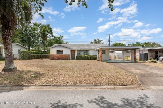 ranch-style home featuring fence, a front lawn, driveway, and a carport