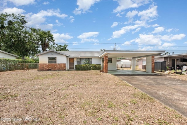 ranch-style house with fence, a front yard, brick siding, concrete driveway, and a carport