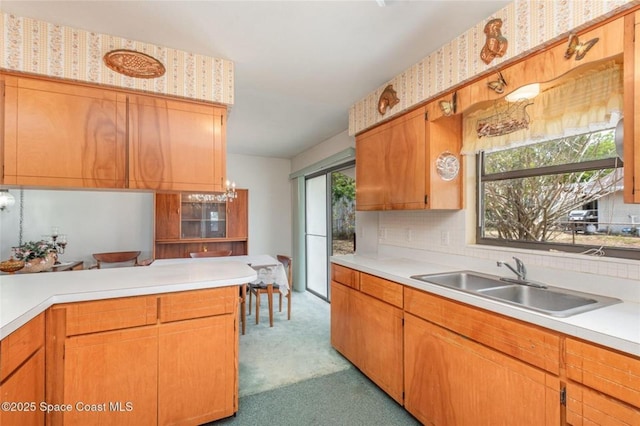 kitchen with brown cabinetry, tasteful backsplash, a sink, light countertops, and carpet floors