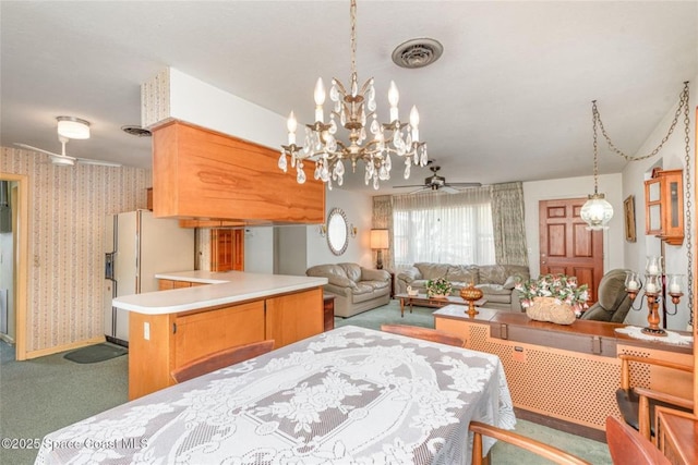 dining room featuring visible vents, carpet floors, ceiling fan with notable chandelier, and wallpapered walls