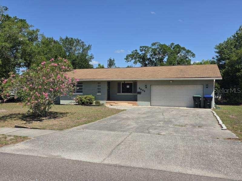 2523 Falkner Rd, Orlando, FL 32810 - ranch-style home with concrete driveway, an attached garage, a front lawn, and stucco siding