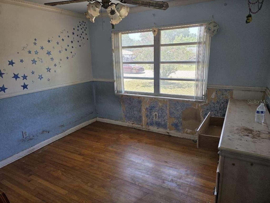 2523 Falkner Rd, Orlando, FL 32810 - unfurnished dining area featuring baseboards, ornamental molding, a ceiling fan, and wood finished floors