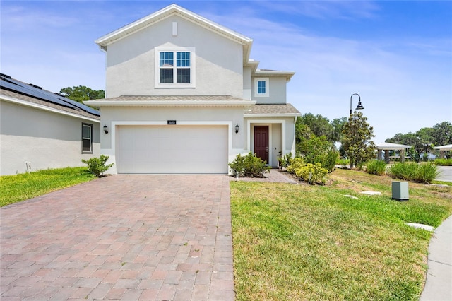 traditional-style house featuring a garage, stucco siding, a front lawn, and decorative driveway